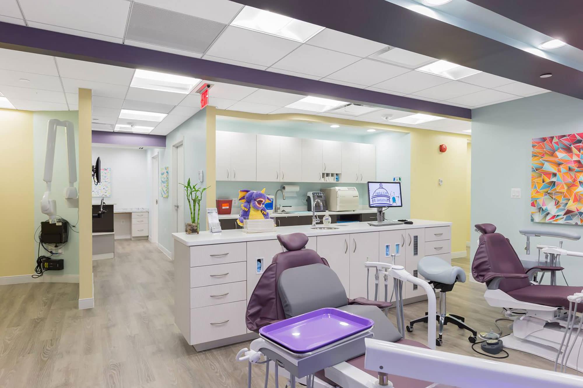 two purple dental examination chairs with white cabinets in the background