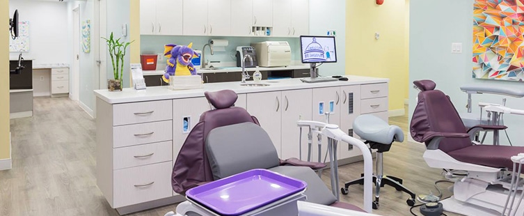 two purple dental examination chairs with white cabinets in the background